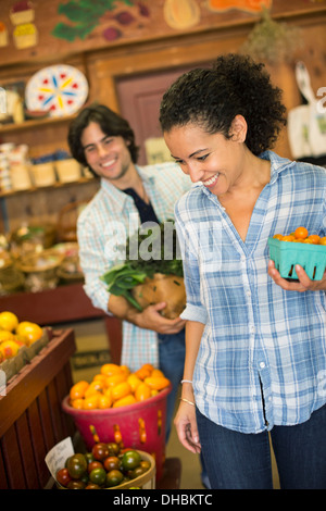 Deux personnes avec des paniers de tomates et de légumes verts à feuilles frisées. Travailler sur une ferme biologique.