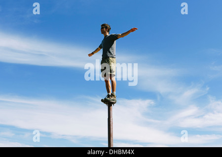 Homme debout en équilibre sur métal en regardant vers le ciel immense surprise sur les lacs alpins de montagne désert Mt Banque D'Images