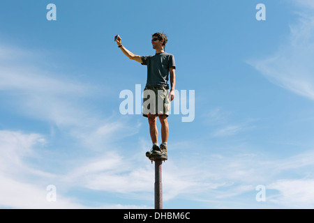 Homme debout en équilibre sur métal en regardant vers le ciel immense surprise sur les lacs alpins de montagne désert Mt Banque D'Images