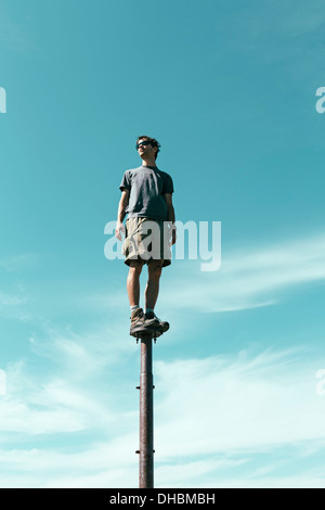 Homme debout en équilibre sur métal à la grande surprise du ciel vers les lacs alpins de montagne désert Mt Banque D'Images