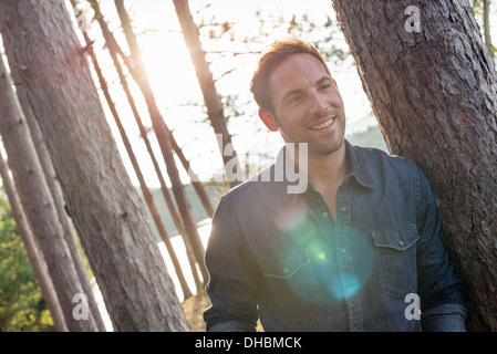 Des arbres sur les rives d'un lac. Un homme souriant à la caméra. Banque D'Images