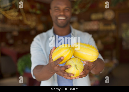 Une ferme la culture et la vente de légumes et fruits biologiques. Un homme à rayures la récolte de courges. Banque D'Images