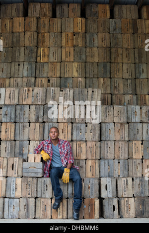 Une basse-cour. Une pile de caisses en bois traditionnels pour l'emballage des fruits et légumes. Un homme assis sur une caisse d'emballage. Banque D'Images