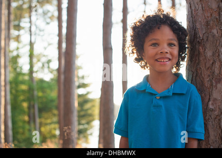 Des arbres sur les rives d'un lac. Un enfant debout parmi les arbres. Banque D'Images