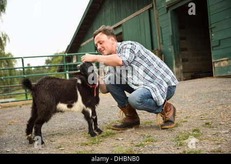 Une ferme biologique dans les Catskills. Un homme avec une petite chèvre noire. Banque D'Images