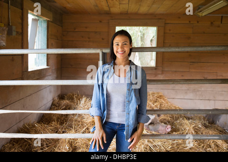 Une ferme biologique dans les Catskills. Une femme à côté d'un cochon dans un stylo, debout dans une paille. Banque D'Images