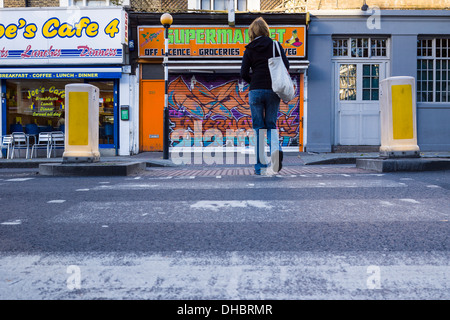 Une femme traverse un Pelican Crossing sur la Caledonian Road à Islington au nord de Londres. Banque D'Images