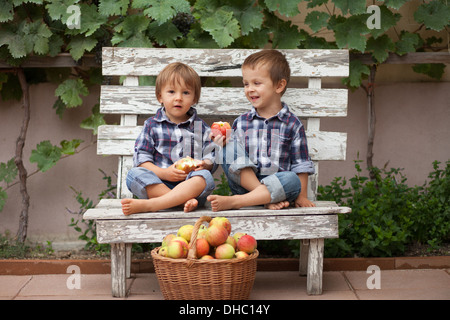 Deux garçons avec un panier de pommes, assise sur un banc Banque D'Images