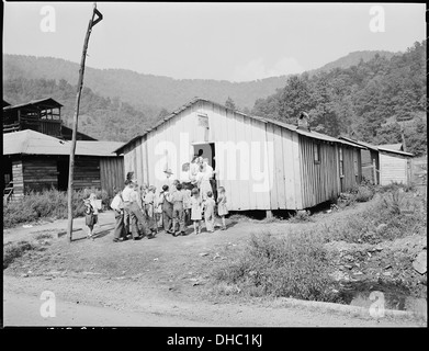 On voit des enfants se rendre à l'école du dimanche à l'église pentecôtiste de Dieu à Lejunior, dans le comté de Harlan, au Kentucky. Cette photographie illustre l'activité religieuse de la communauté et l'importance de la foi dans la vie rurale durant cette période. Banque D'Images