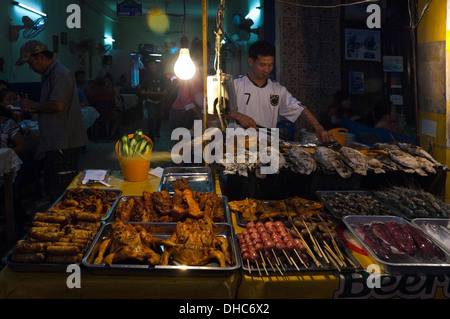 Portrait d'un horizontal Lao barbecue local l'homme poisson entier sur un gril à un café de la rue la nuit. Banque D'Images