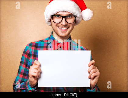 Hipster guy dans le chapeau de Père Noël tenant une feuille de papier. Mine d'espace Banque D'Images