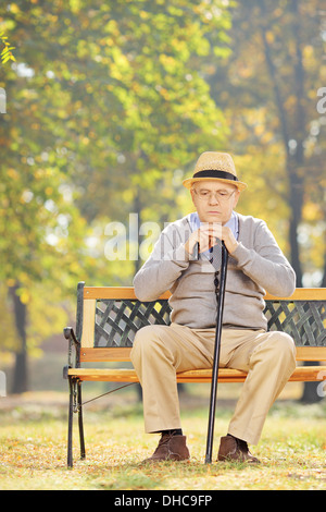Happy man avec une canne assis sur un banc en bois dans un parc Banque D'Images