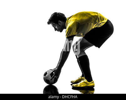 Un brésilien football soccer player jeune homme la préparation de pied franc en silhouette studio sur fond blanc Banque D'Images