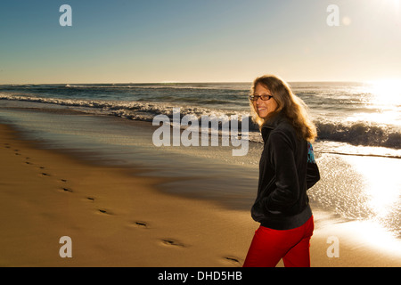 Blonde mature woman walking on beach au lever du soleil. Banque D'Images