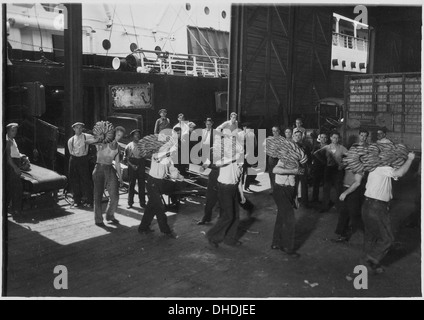 Des débardeurs de New York transportent des bananes depuis des cargos, en utilisant des méthodes traditionnelles de manutention et de transport des marchandises dans les zones portuaires. L'image capture le processus de la logistique maritime. Banque D'Images