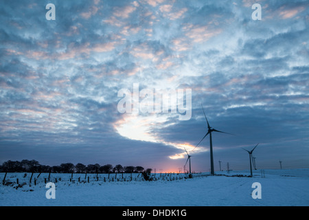 Éoliennes dans un champ silhouetté contre un hiver spectaculaire coucher du soleil Banque D'Images