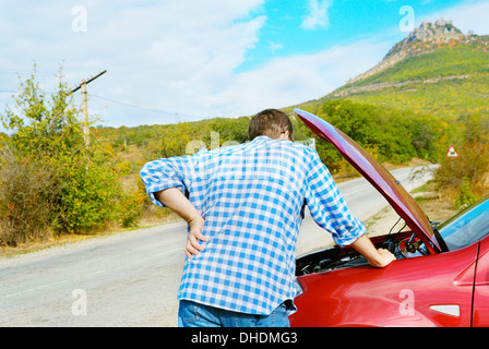 Homme adulte est debout près de sa voiture cassée en attente de remorquer Banque D'Images