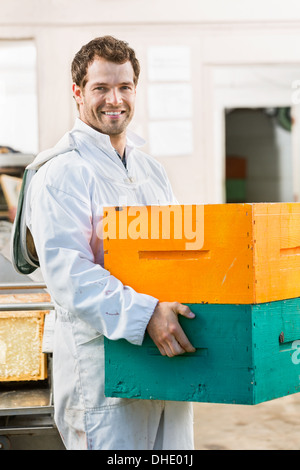 Heureux homme apiculteur Réalisation pile de caisses d'abeilles Banque D'Images