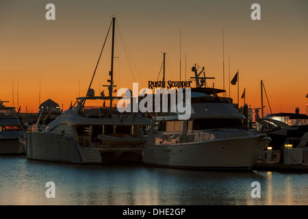 Le ciel est orange lever du soleil derrière les bateaux de plaisance amarrés dans l'une des marinas de l'Inner Harbor de Baltimore, Maryland. Banque D'Images