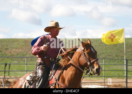 Cowboy avec arme à cheval et le nouveau drapeau du Mexique, montée d'une compétition de tir, fin du sentier du Jubilé de l'Ouest sauvage, Albuquerque, NM, USA Banque D'Images