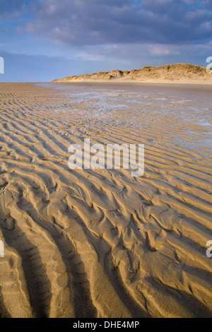 Les patrons de sable au coucher du soleil le long de la plage déserte Quai Mad à Formby Point. Les crêtes dans le sable sont soulignés par le coucher du soleil Banque D'Images