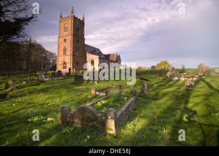 L'église St Mary Vierge Hanbury. Le faible soleil au coucher du soleil jette de longues ombres sur les tombes dans le cimetière. Banque D'Images