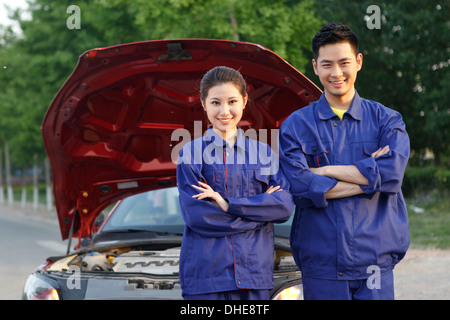 Jeune homme et la jeune femme le personnel de réparation automobile Banque D'Images