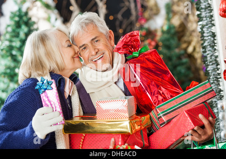 Femme au sujet d'embrasser l'homme Holding Presents Banque D'Images
