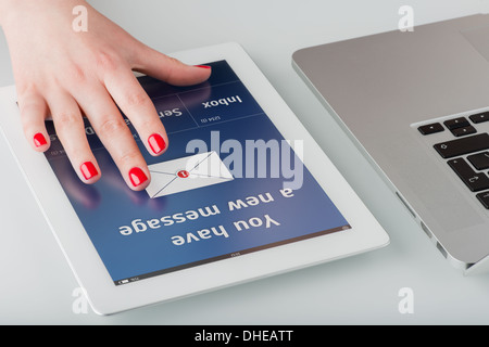 Woman's hand avec manucure rouge ouvre un nouvel e-mail sur un ordinateur tablette. Banque D'Images