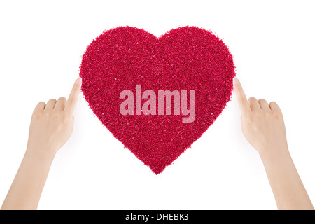 Woman's hands rendant le coeur de sable rouge par index sur fond blanc. Banque D'Images