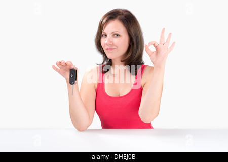 Happy young woman is holding car keys, montrant ok geste et regardant la caméra Banque D'Images