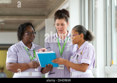 Un groupe de trois infirmières discuter un travail notes patients UK Banque D'Images