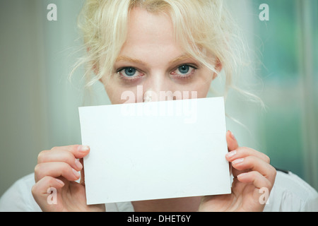 Jeune femme tenant une carte vierge sur son visage Banque D'Images