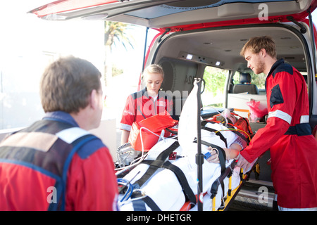 Femme de levage des paramédics sur civière en ambulance Banque D'Images