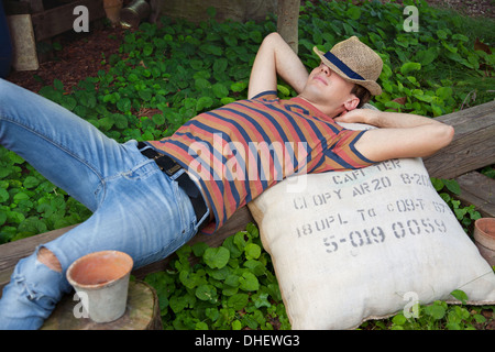Young man wearing straw hat lying on sac Banque D'Images