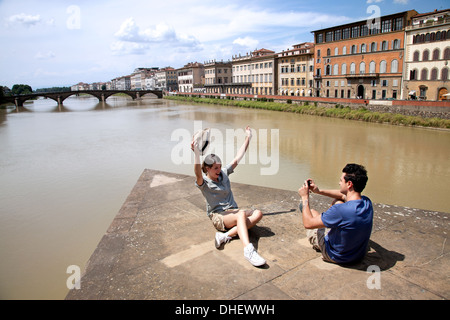 Man photographing woman avec Ponte alle Grazie en arrière-plan, Florence, Toscane, Italie Banque D'Images