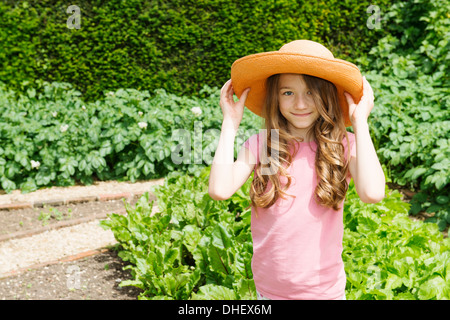 Girl wearing straw hat in garden Banque D'Images