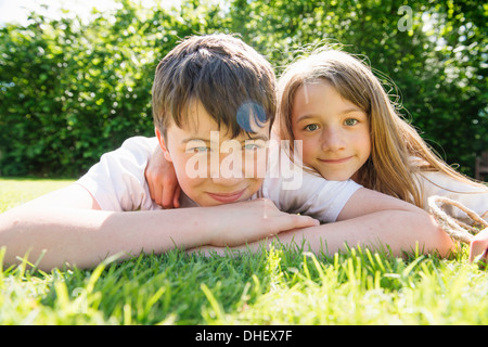 Portrait de frère et sœur lying on grass Banque D'Images