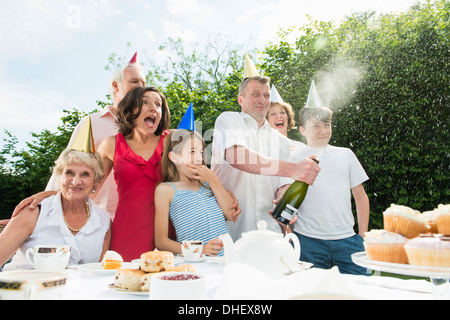 Family celebrating birthday, man opening champagne Banque D'Images