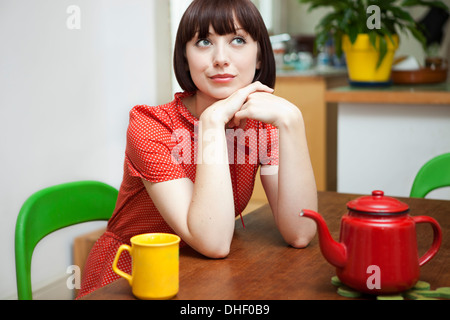 Portrait of young woman sitting at table de cuisine Banque D'Images