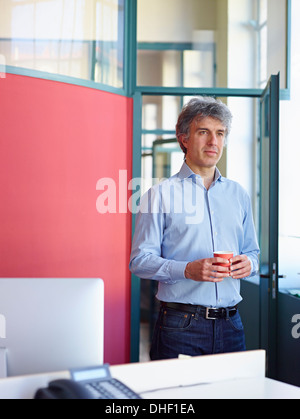 Businessman holding coffee in office Banque D'Images