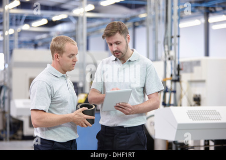 Deux travailleurs looking at digital tablet in engineering warehouse Banque D'Images