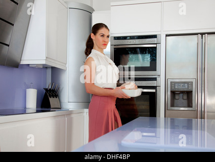 Jeune femme tenant un plat à rôtir dans la cuisine Banque D'Images