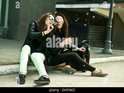 Deux jeunes woman blowing bubbles on street Banque D'Images