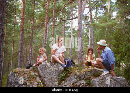 Family sitting on rocks in forest eating picnic Banque D'Images