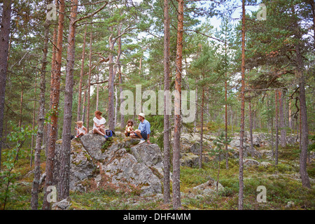 Family sitting on rocks in forest eating picnic Banque D'Images