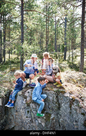 Family sitting on rocks in forest eating picnic Banque D'Images