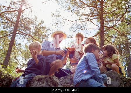 Family having picnic assis sur des rochers Banque D'Images