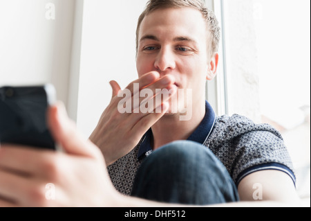 Man blowing kiss at mobile phone Banque D'Images