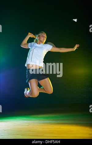 Jeune femme badminton player mid air sur cour Banque D'Images